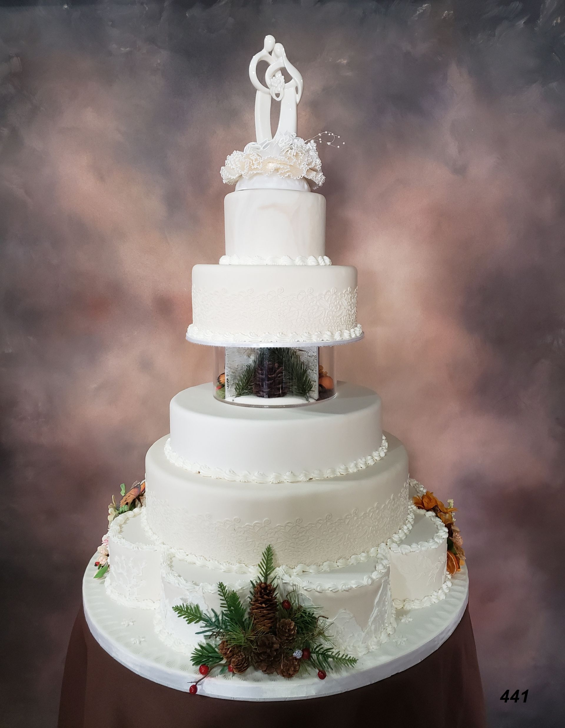 Tall white multi-tier wedding cake with floral decorations and a bride-and-groom topper
