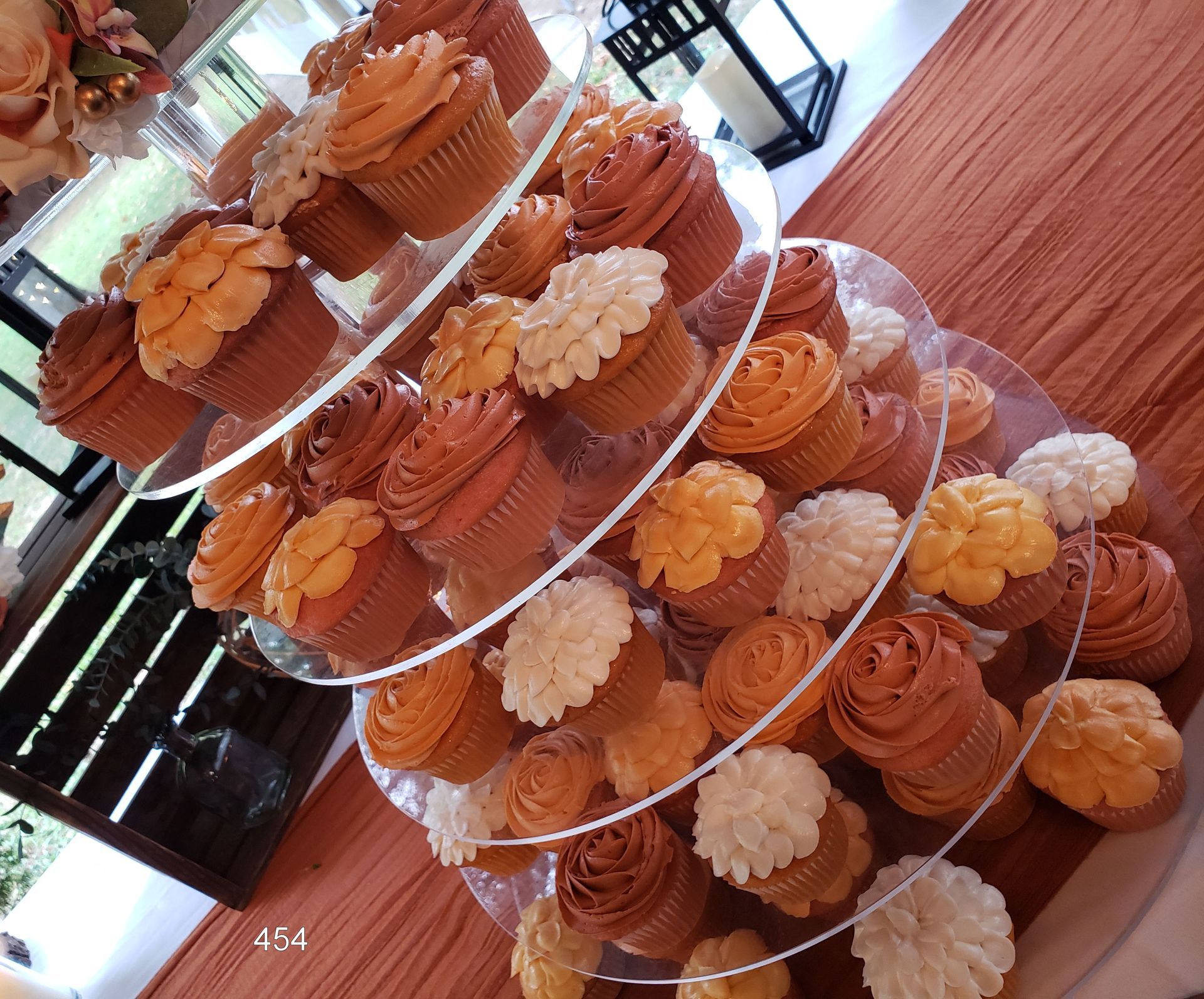 Tiered trays of frosted cupcakes in orange and white on a dessert table