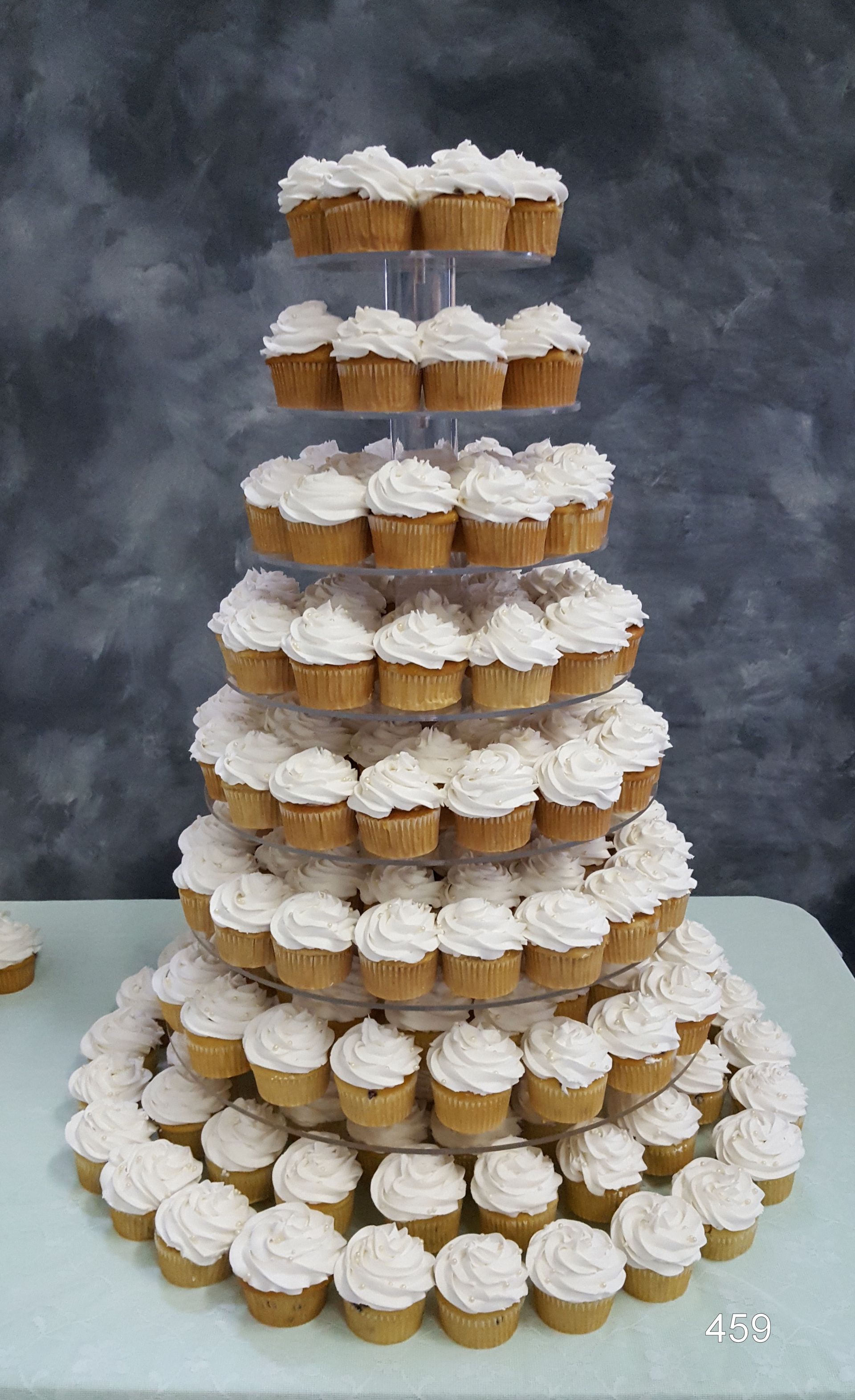 Tiered display of frosted cupcakes on a table, arranged in a tall pyramid tower