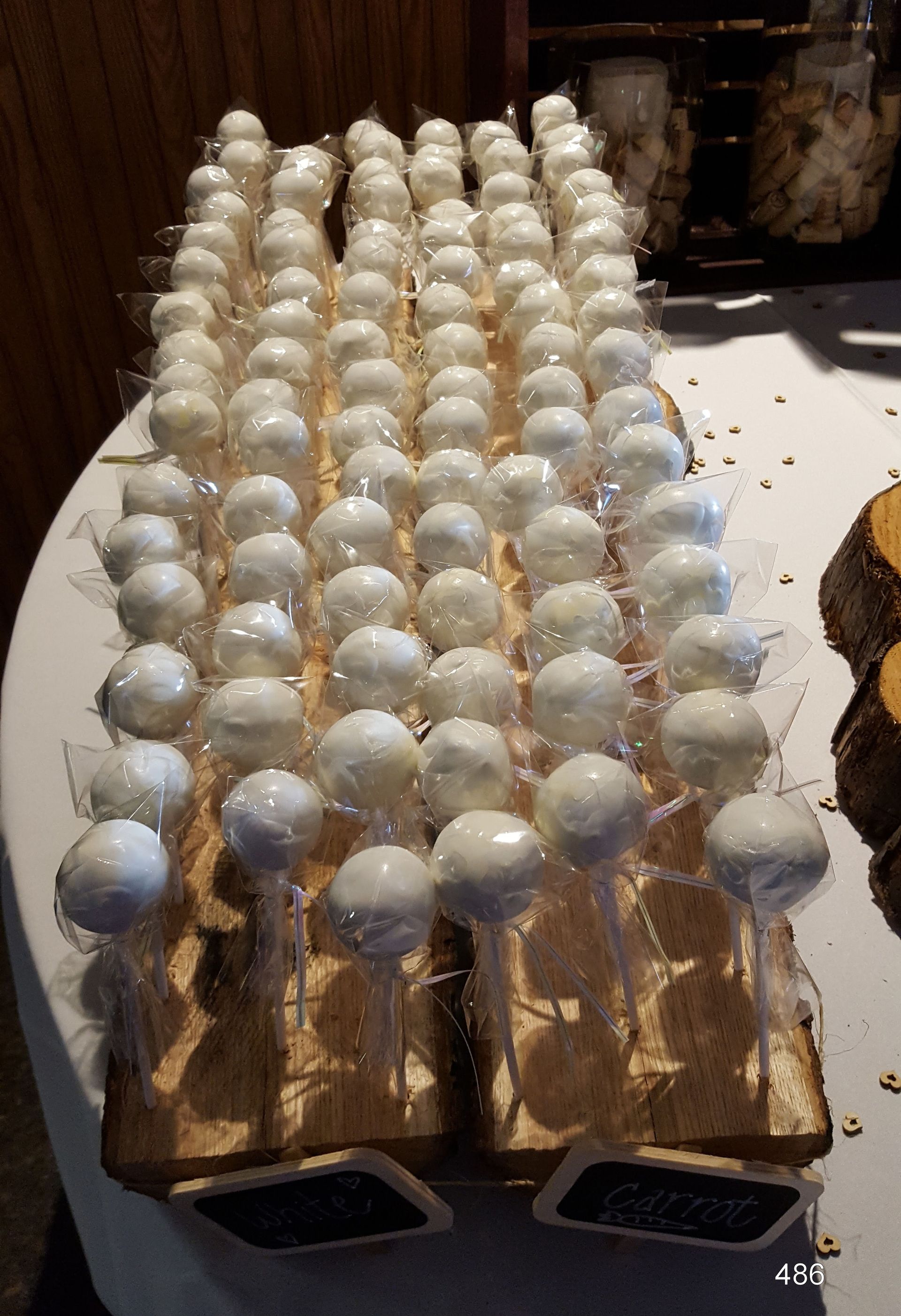 Rows of white spherical items arranged on a wooden tray in a dim indoor setting
