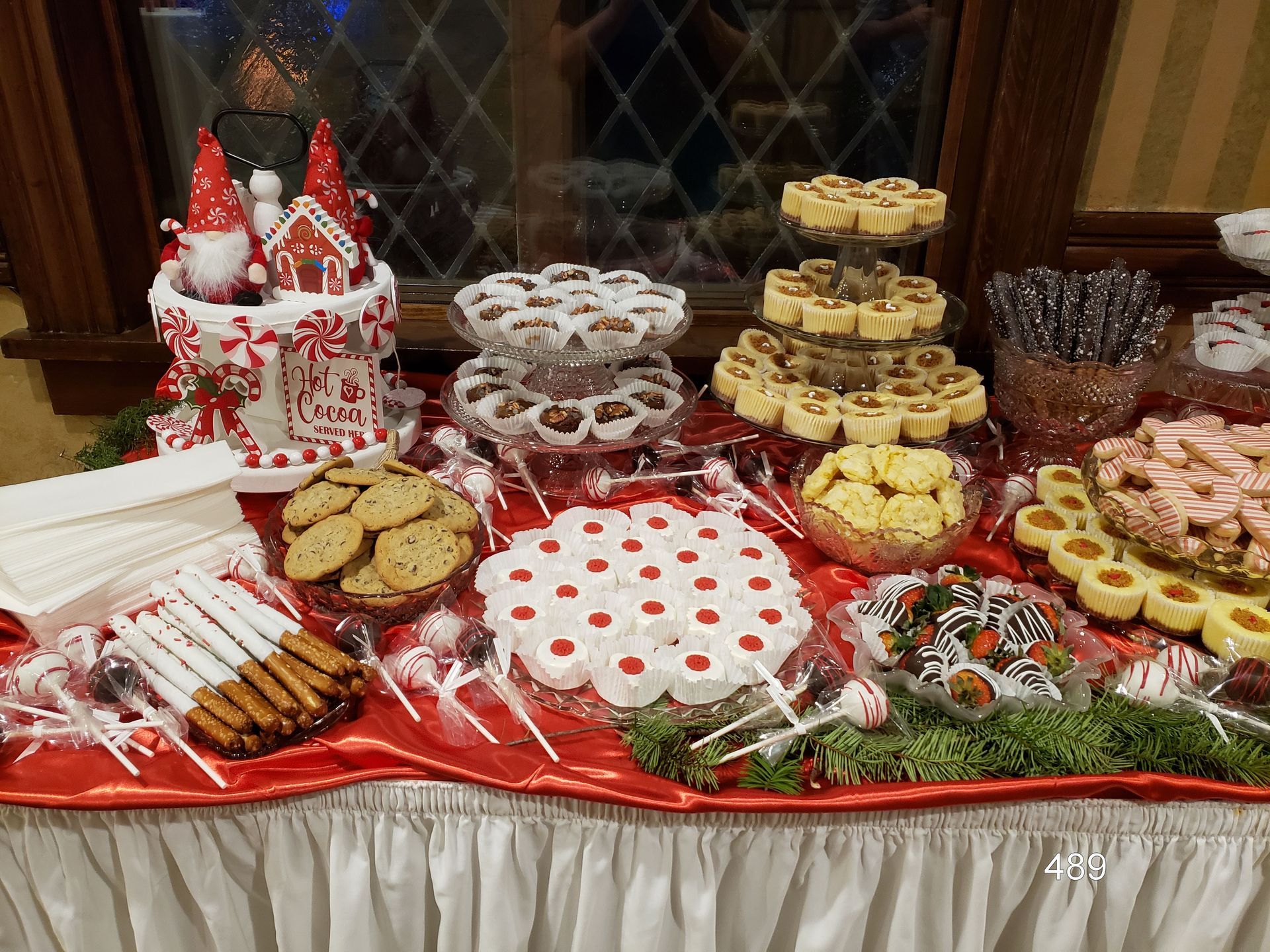 Holiday dessert table with cookies, candy canes, and decorated treats on a red tablecloth
