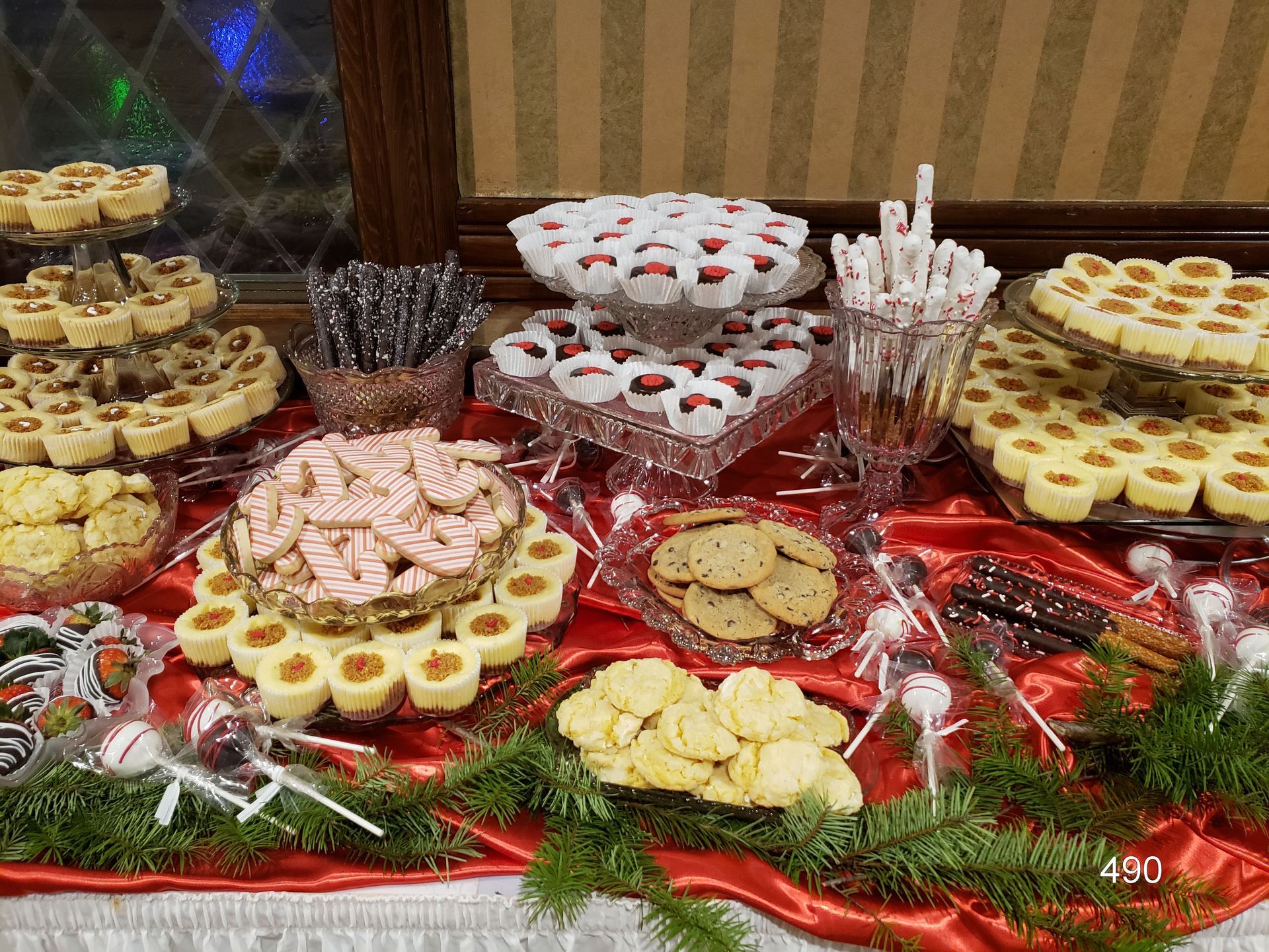 Dessert buffet with assorted cookies and pastries on a red tablecloth, arranged on a holiday display
