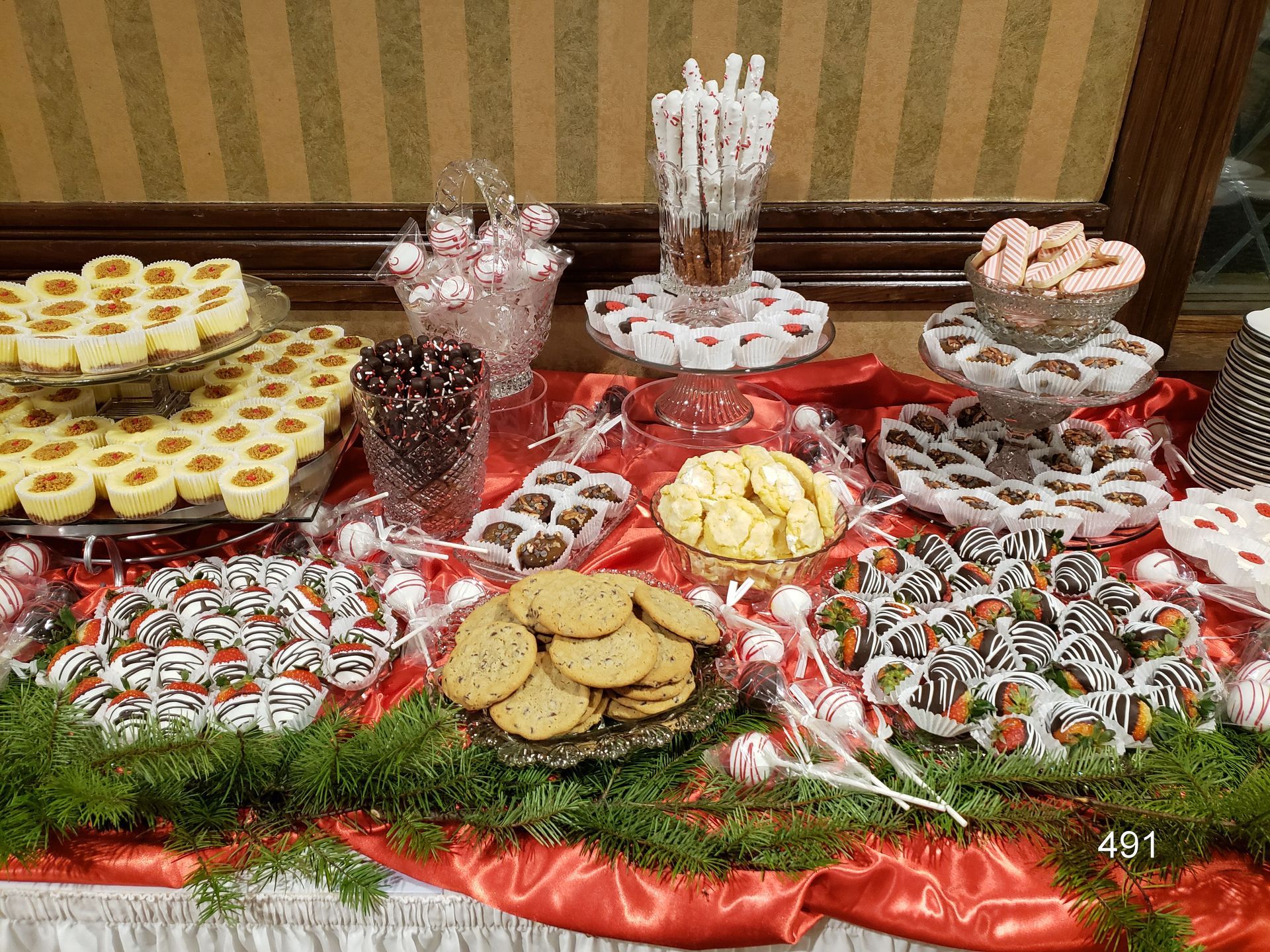 A buffet table with assorted desserts and cookies on red and white decorative platters.
