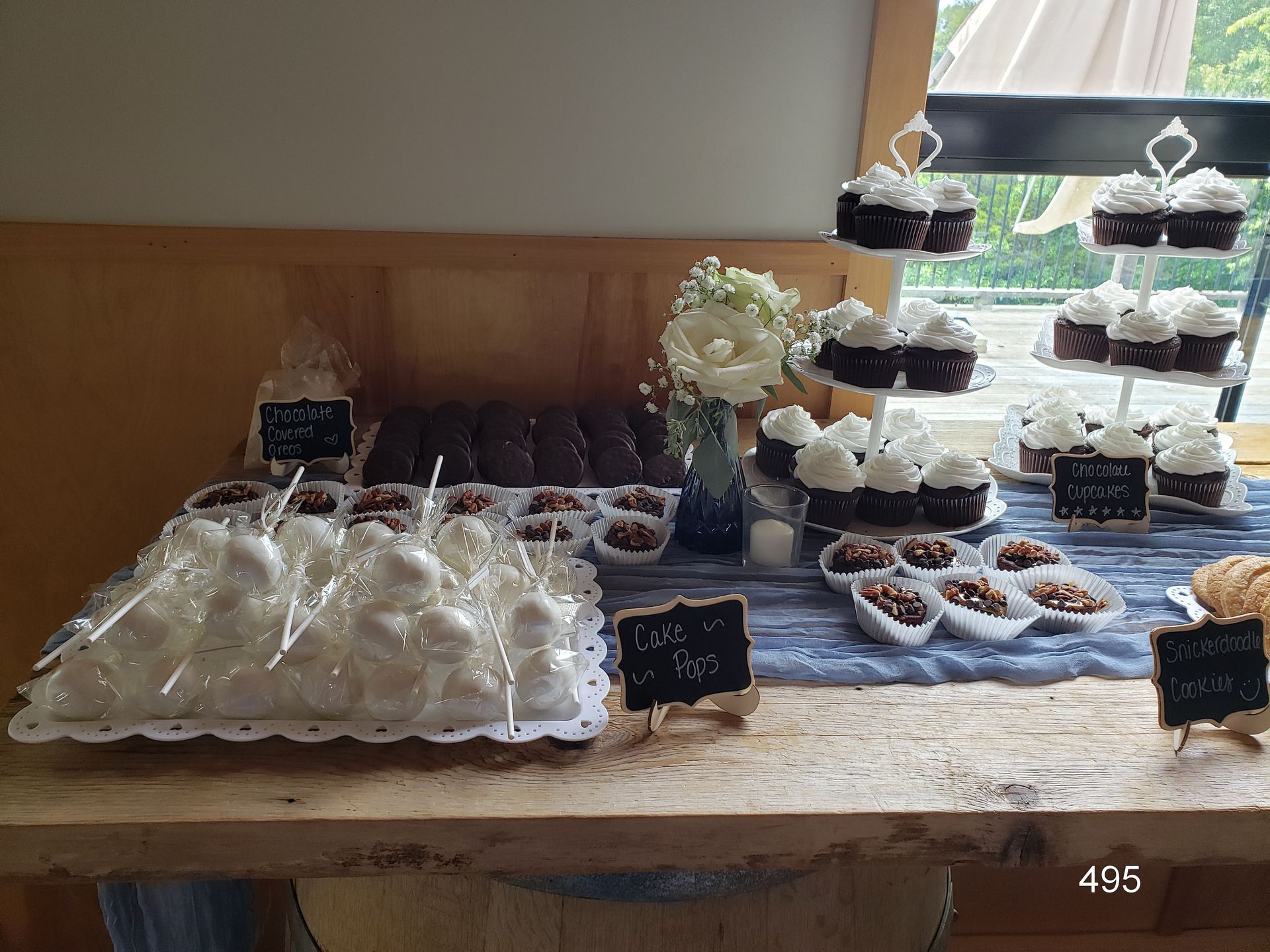 Dessert table with cupcakes, pastries, and white frosting treats on tiered trays and a wooden table