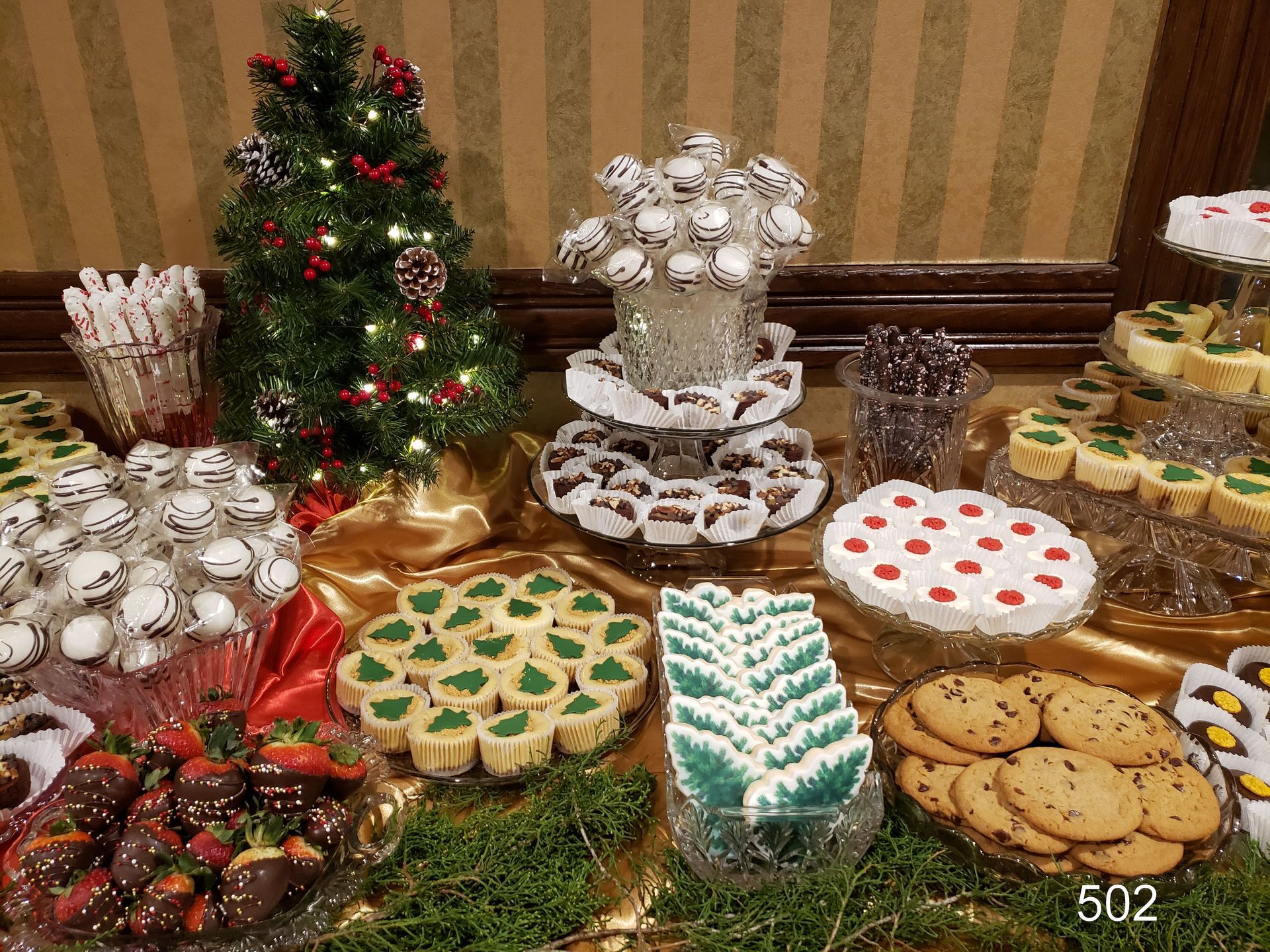 Assorted holiday cookies and desserts arranged on a table with a small decorated Christmas tree.