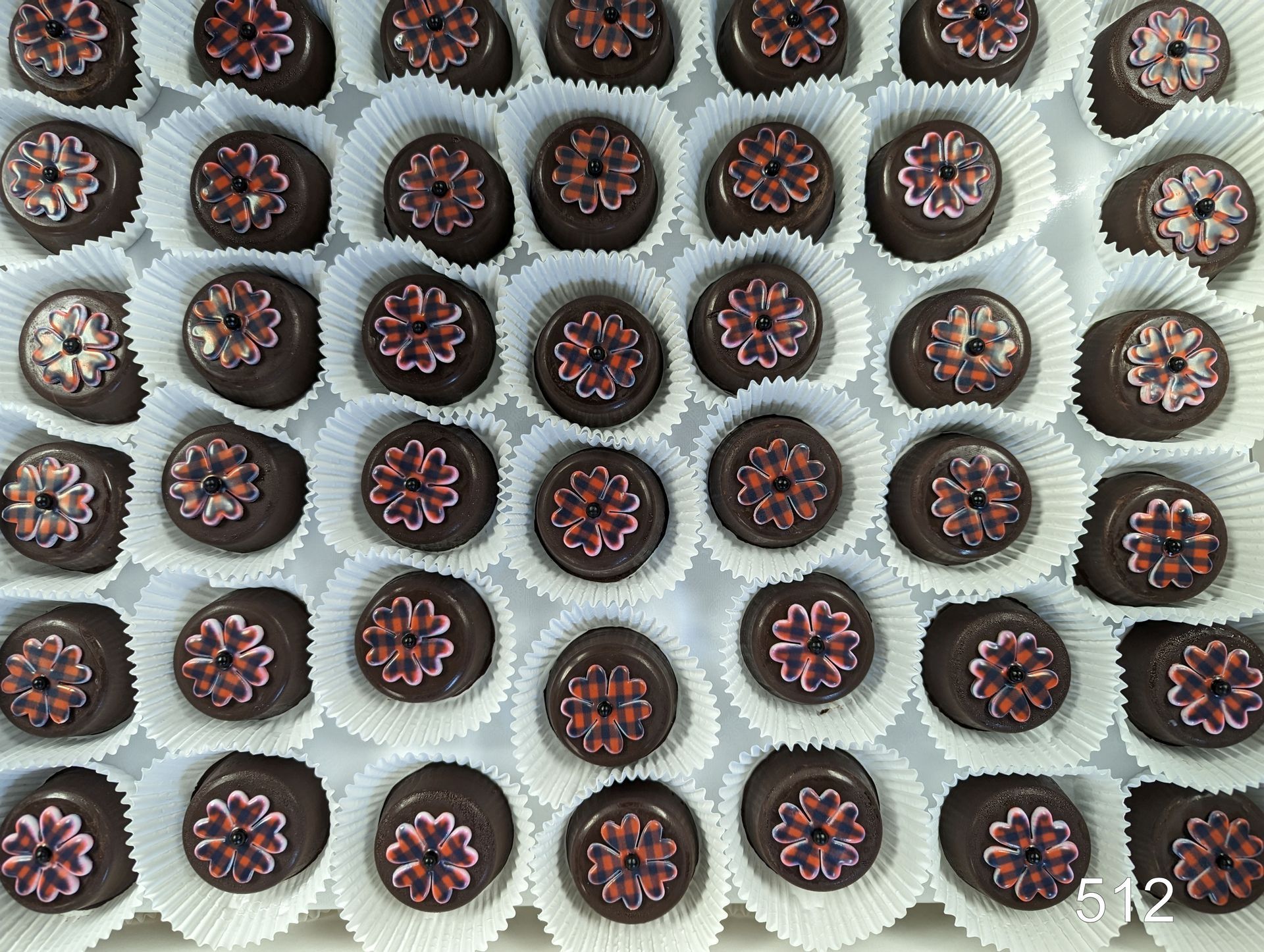 Rows of chocolate cupcakes topped with pink frosting, arranged on a cooling rack