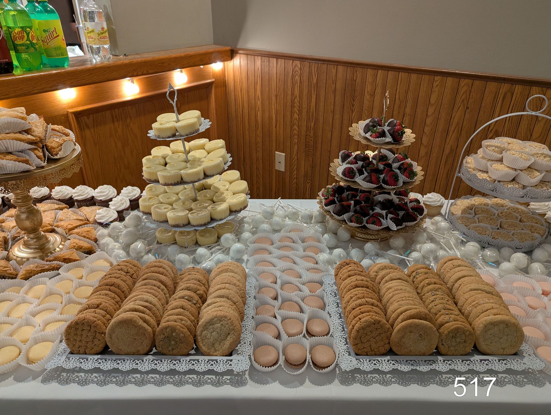 Dessert buffet with trays of cookies, cupcakes, and pastries on a decorated table in a banquet room