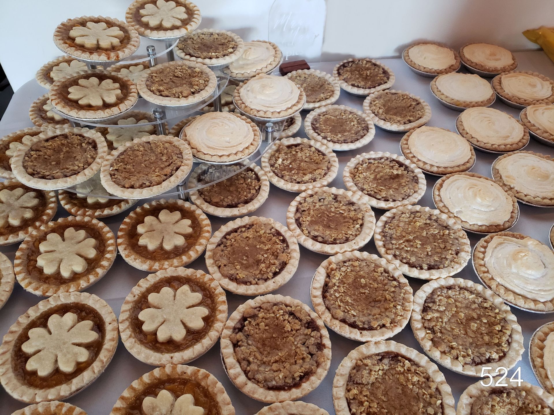 Dozens of round floral and woven wooden coasters or ornaments arranged in rows on a light surface