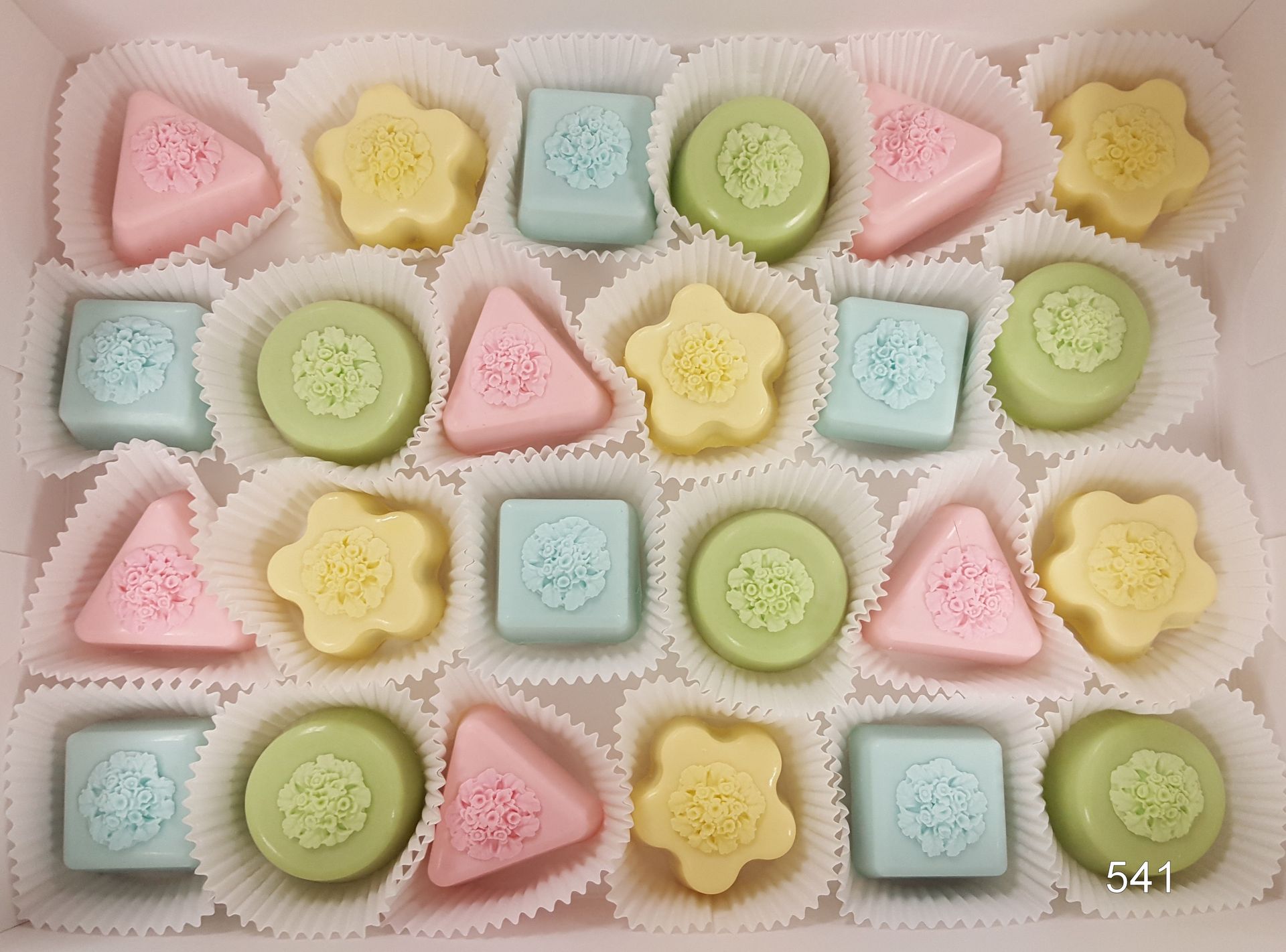 Pastel star, flower, circle, and triangle cookies in a white tray, arranged in neat rows.