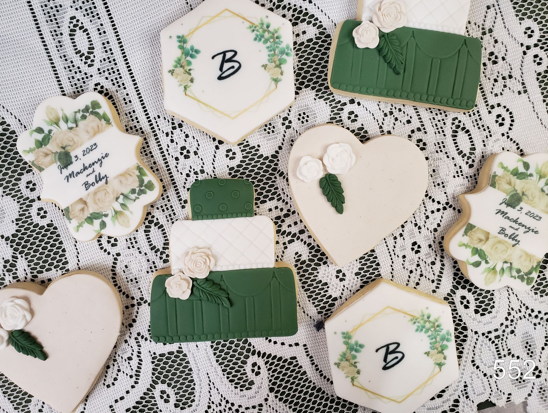 Lace-covered table with white and green floral wedding place cards and heart-shaped tags with initials.