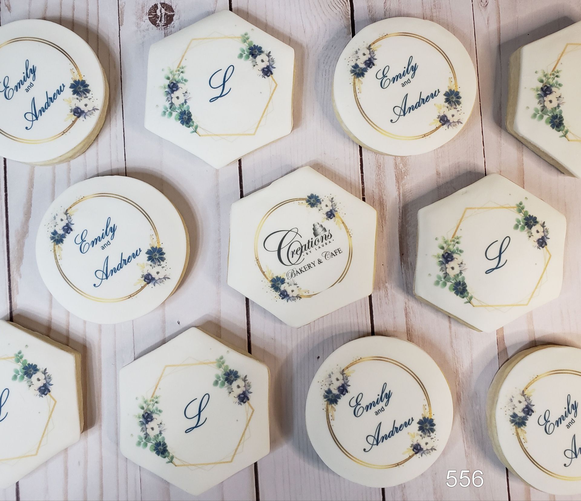 Assorted white and gold hexagonal and round personalized cookies on a wooden surface with floral accents