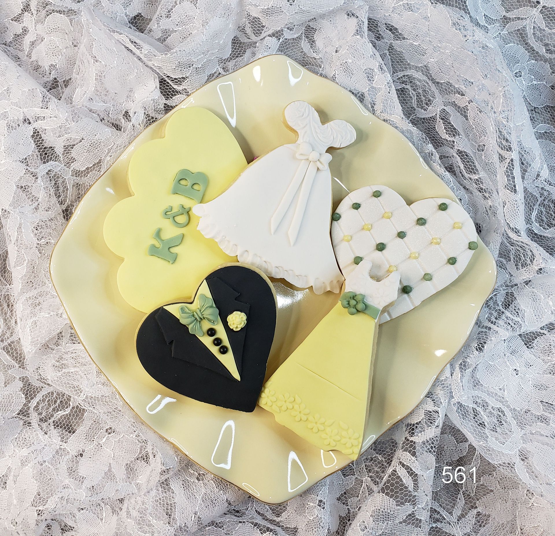 Dessert plate with colorful heart-shaped cookies and a white dress cookie on lace fabric.