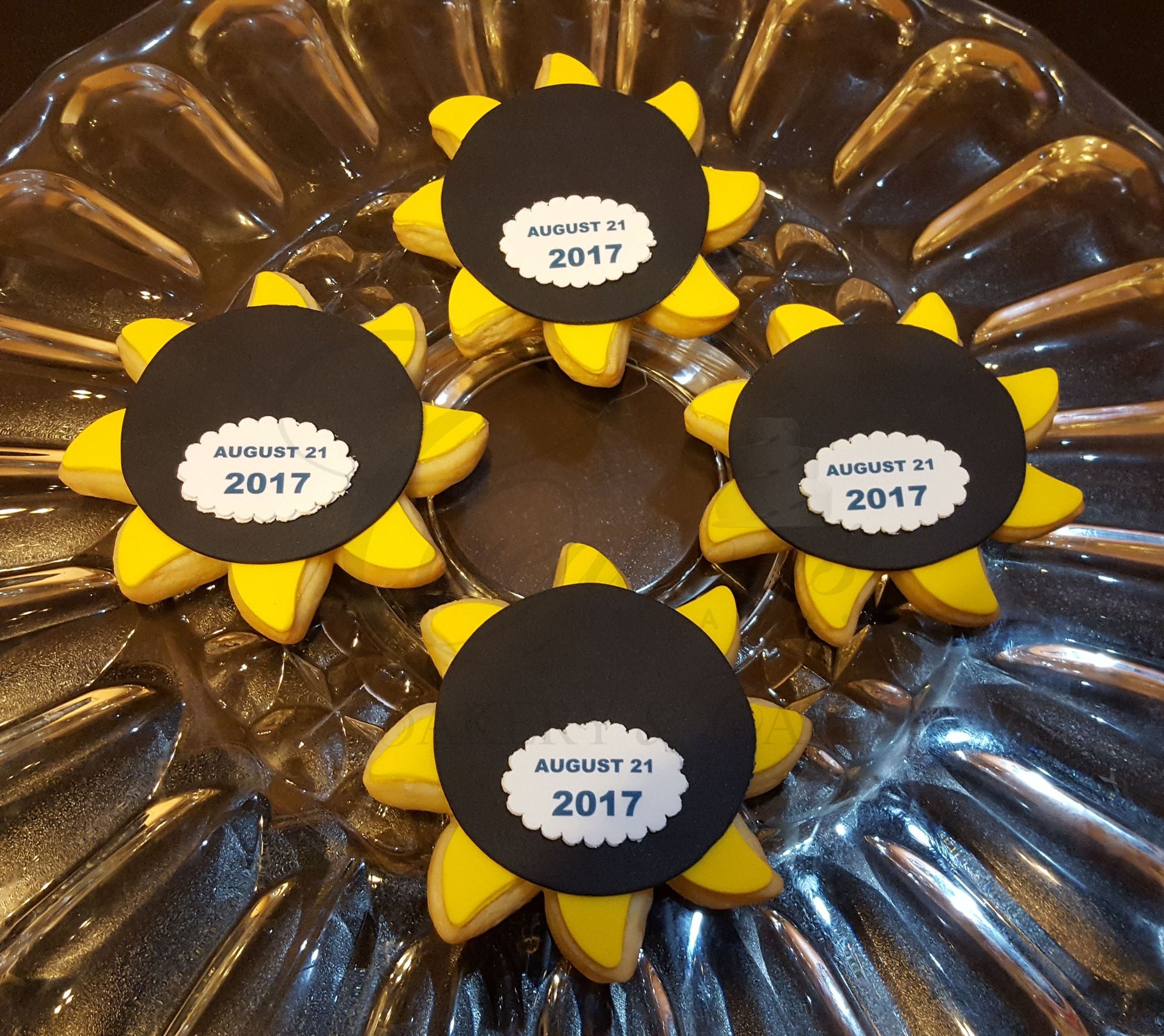 Black-and-yellow flower cookies with “August 2017” labels on a silver platter