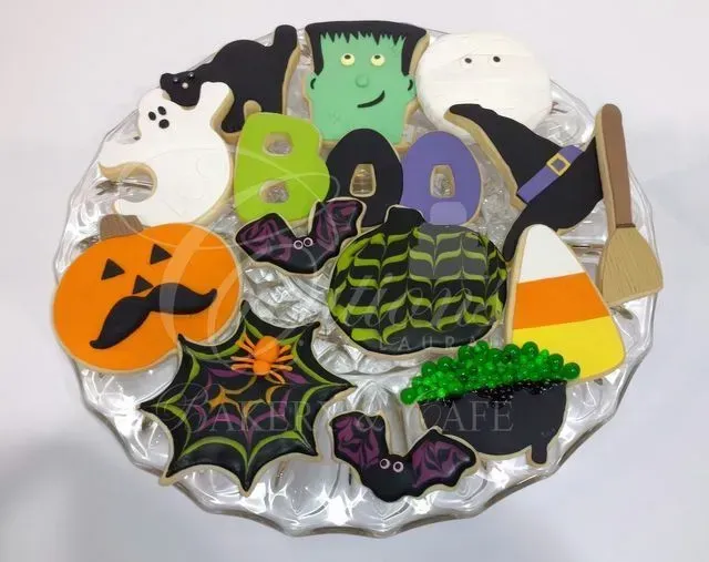 Halloween-themed plate of decorated cookies: ghosts, pumpkins, witch hats, candy corn, and spiders.
