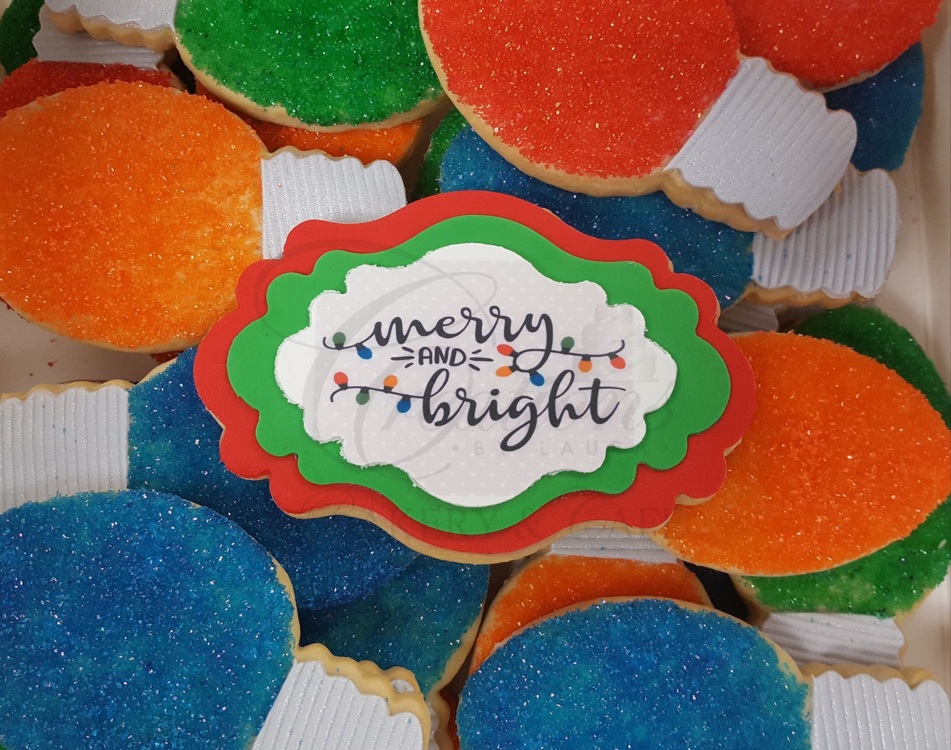 Colorful holiday cookies with a center plaque reading “merry and bright”