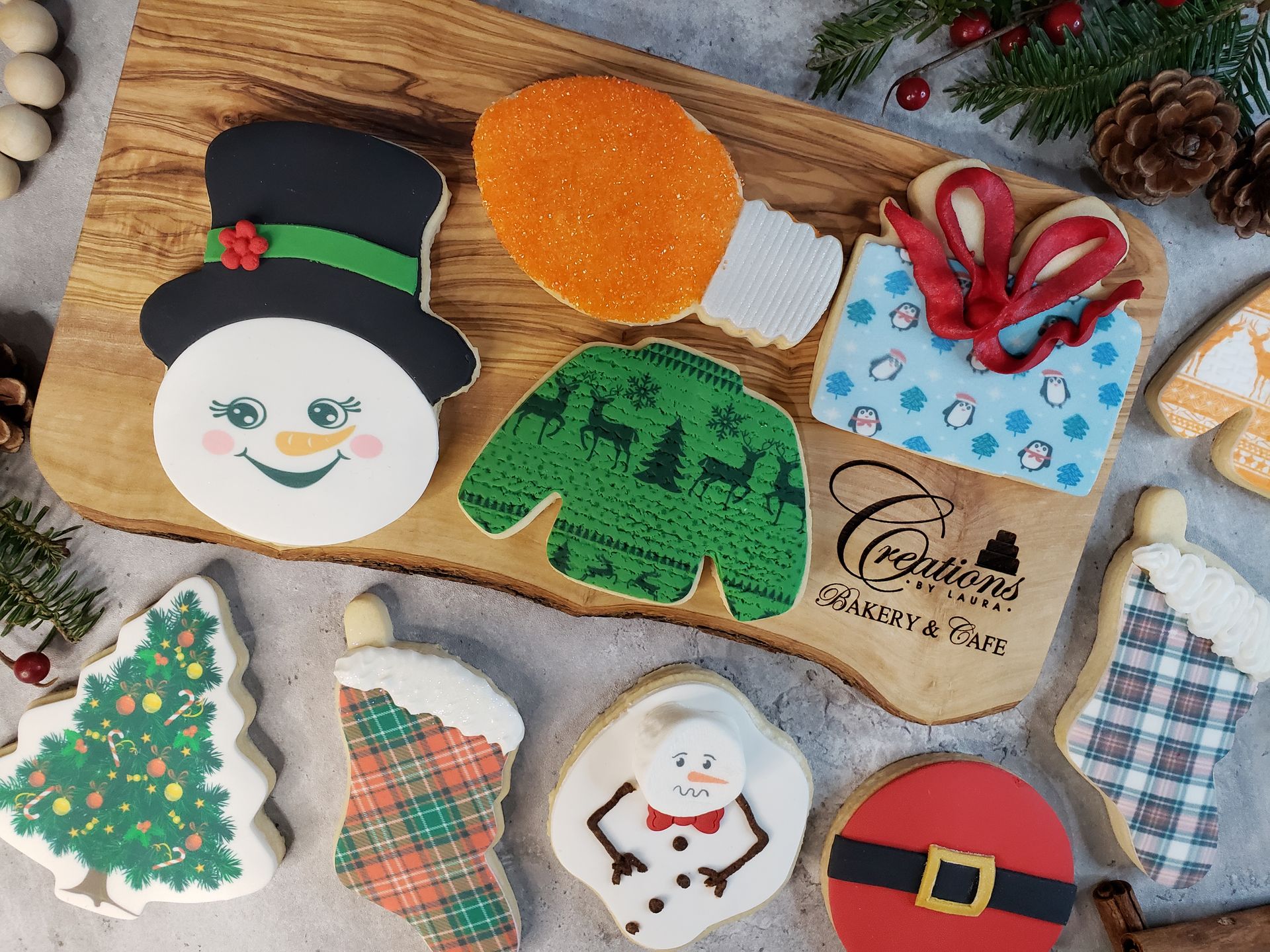Assorted decorated Christmas cookies shaped like Santa, snowman, tree, mitten, and ornaments on a wooden board