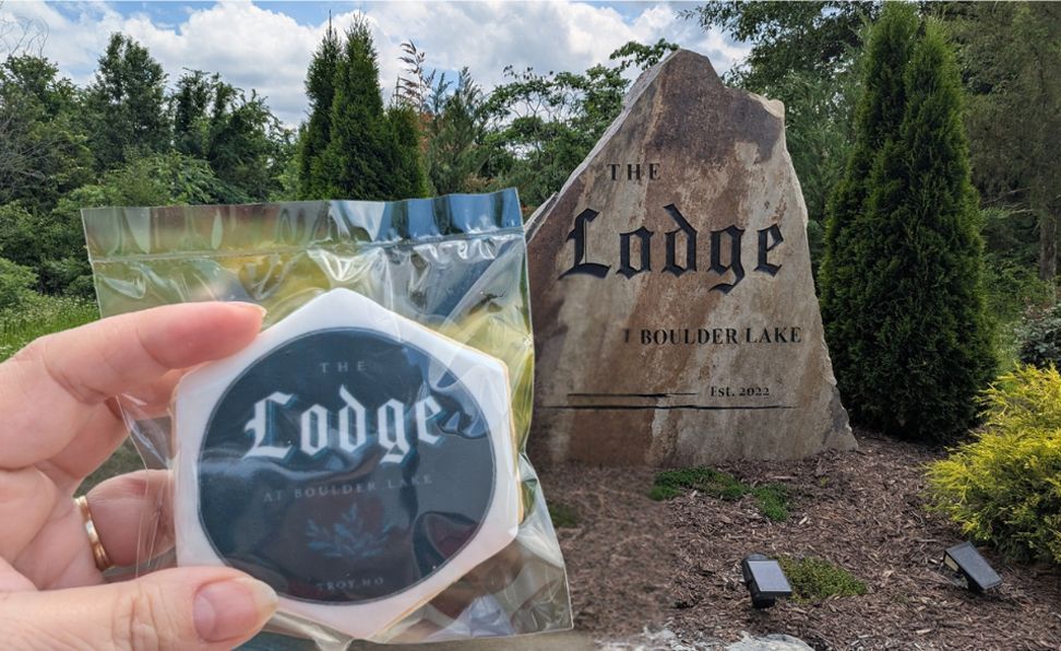 Hand holding a wrapped Lodge cookie in front of a Lodge restaurant sign outdoors