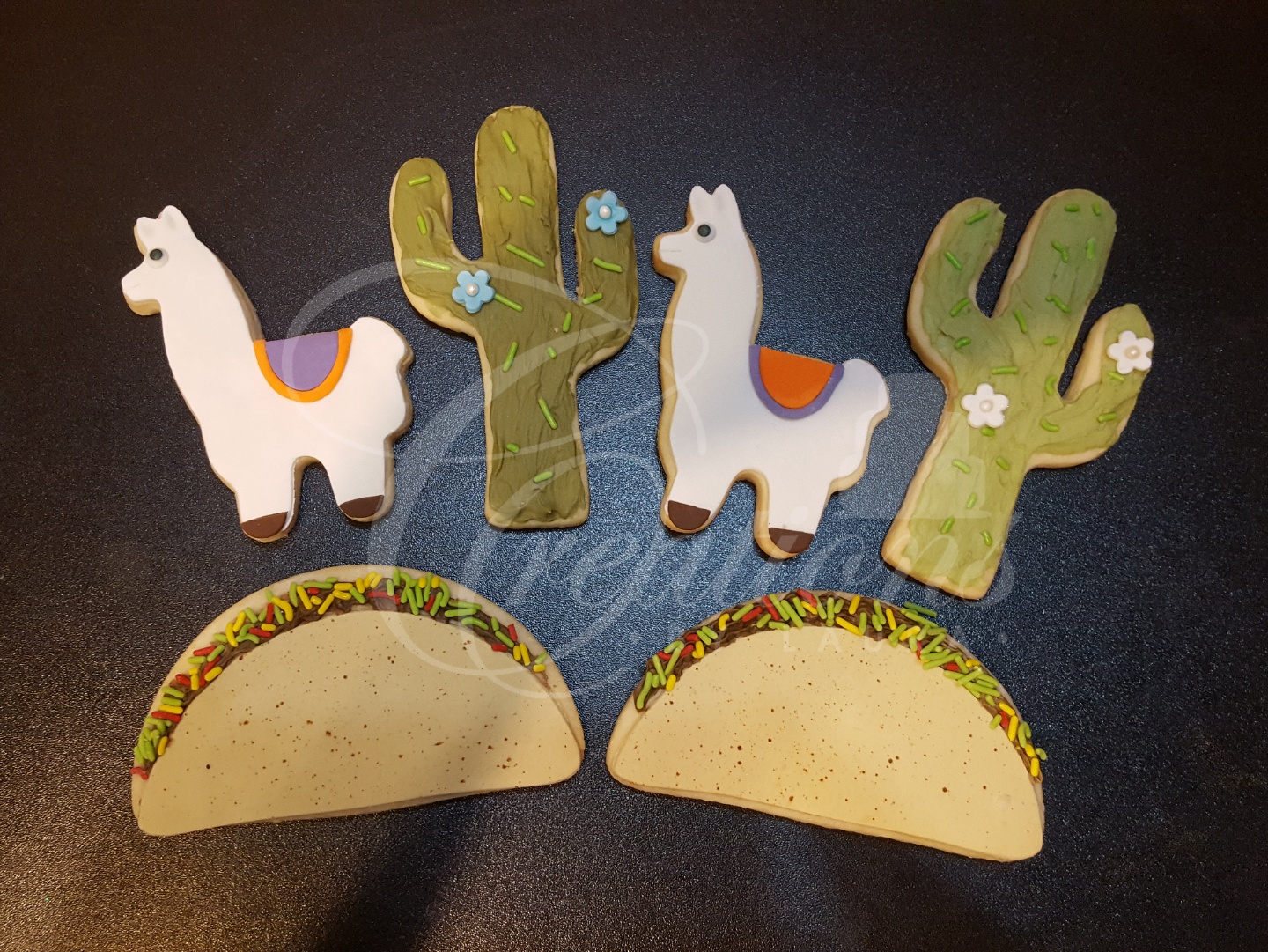 Decorative taco-themed craft with llamas, cacti, and two taco halves on a dark background