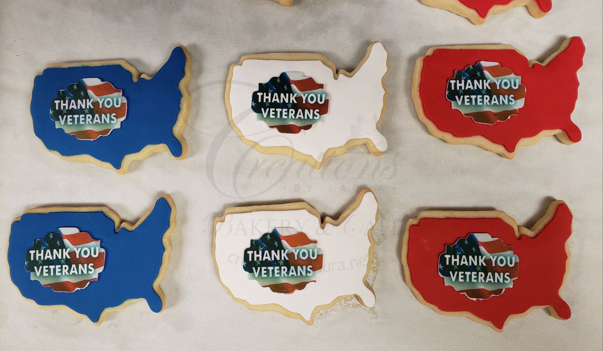 Six “Thank You Veterans” USA-shaped cookies in blue, white, and red on a light surface