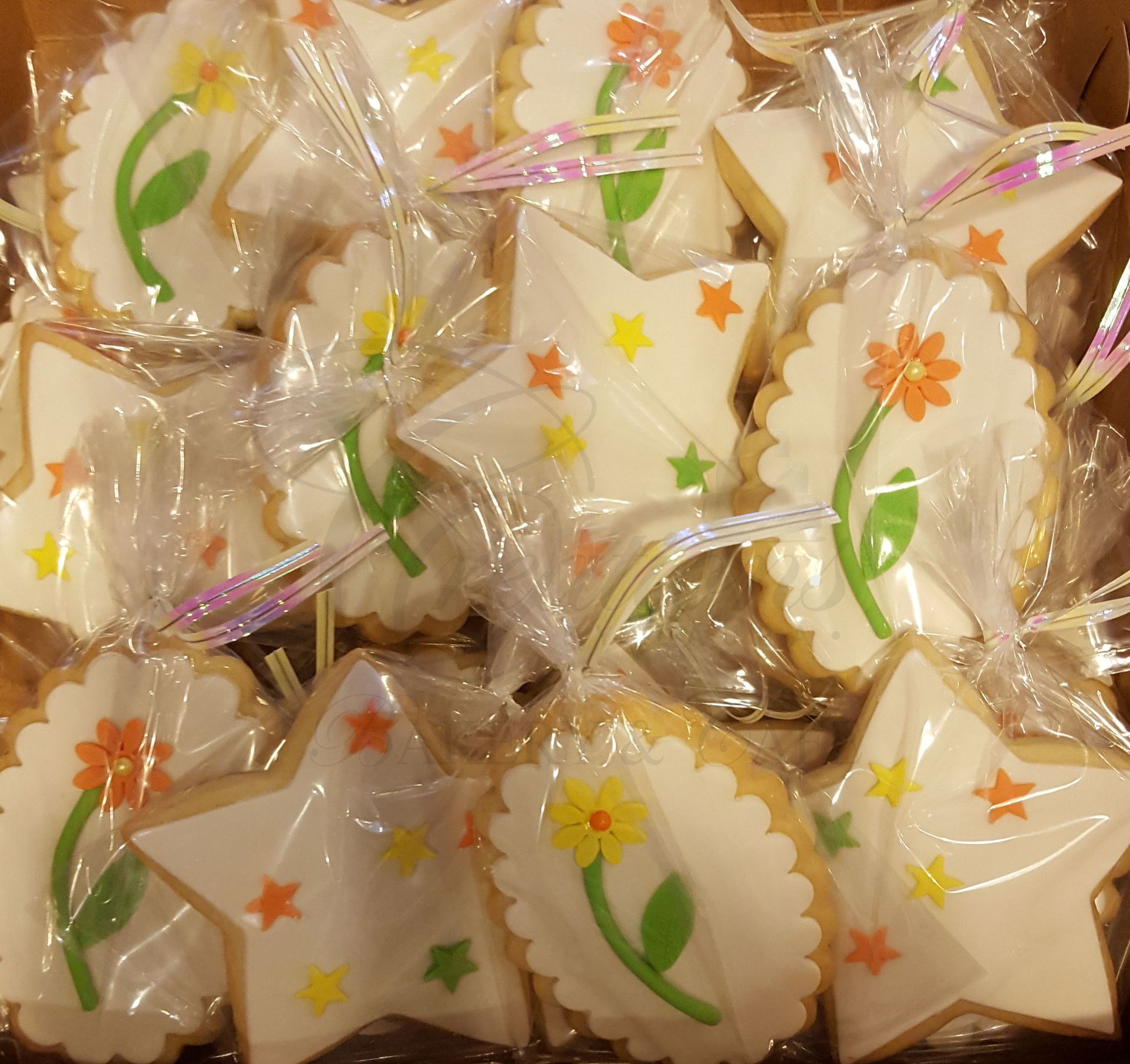 Wrapped star-shaped cookies with white icing, green leaves, and orange flower decorations stacked together