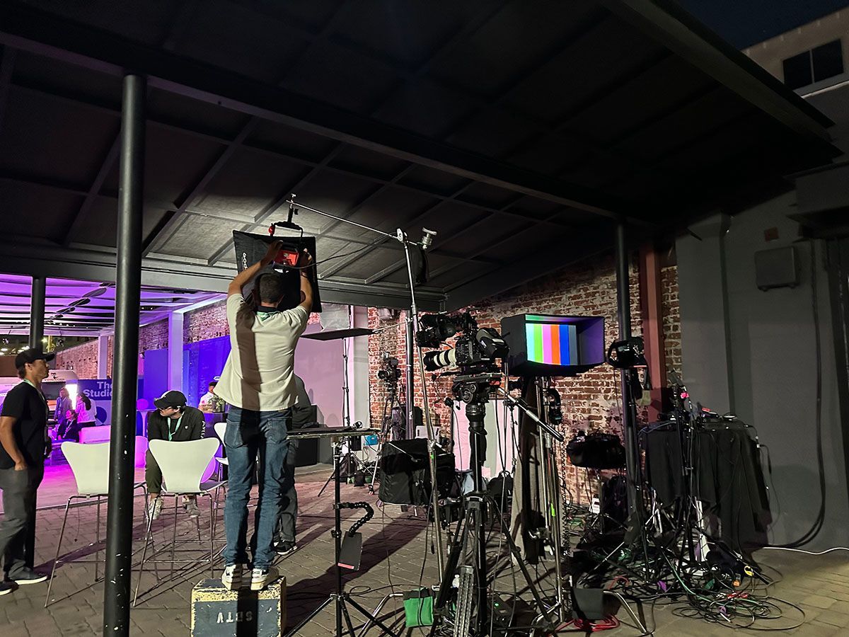 A man is standing under a canopy holding a monitor over his head.