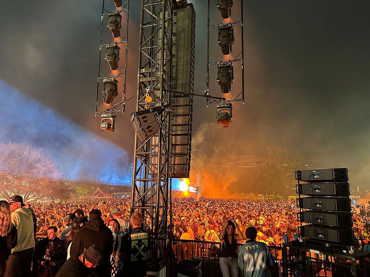 A crowd of people are standing in front of a stage at a concert.