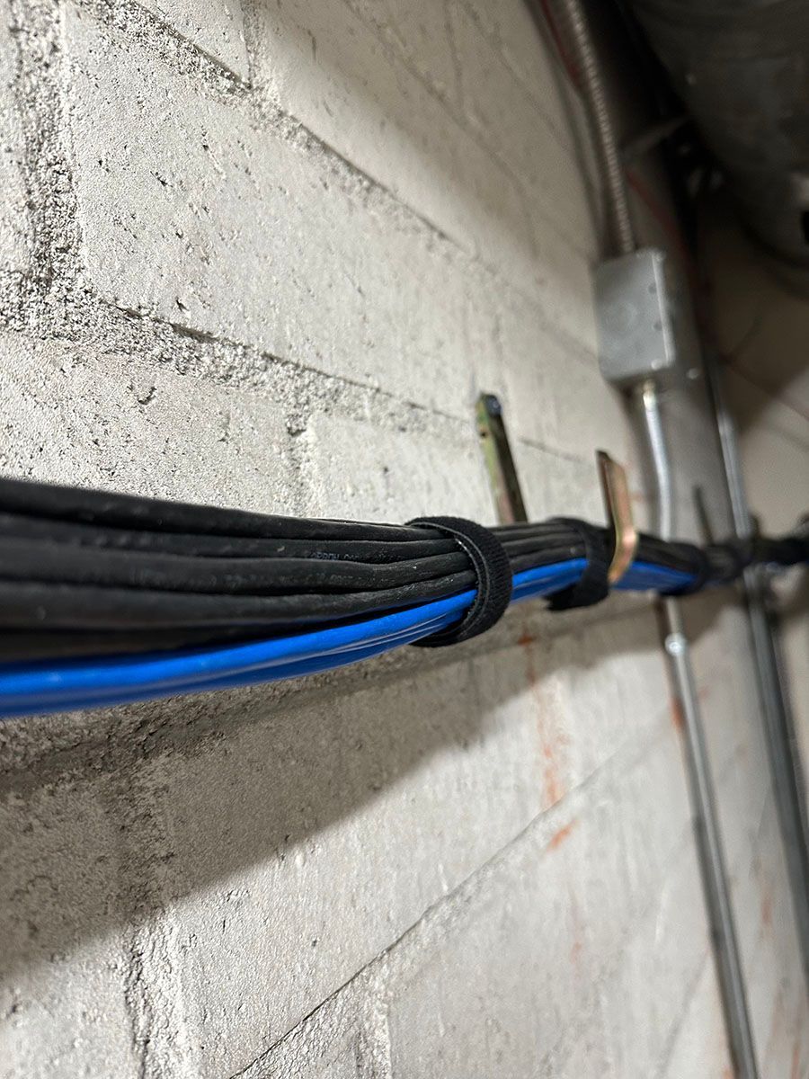 A bunch of wires are hanging on a brick wall.