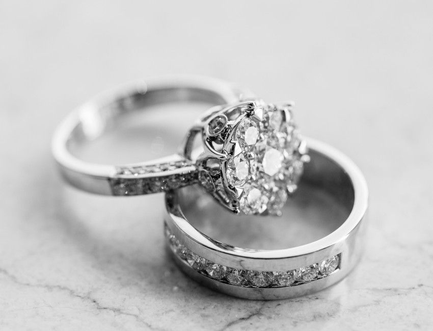 Two diamond rings, one with a large floral cluster, on a marble surface.