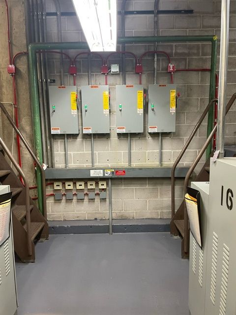 A room with a lot of electrical boxes on the wall and stairs.