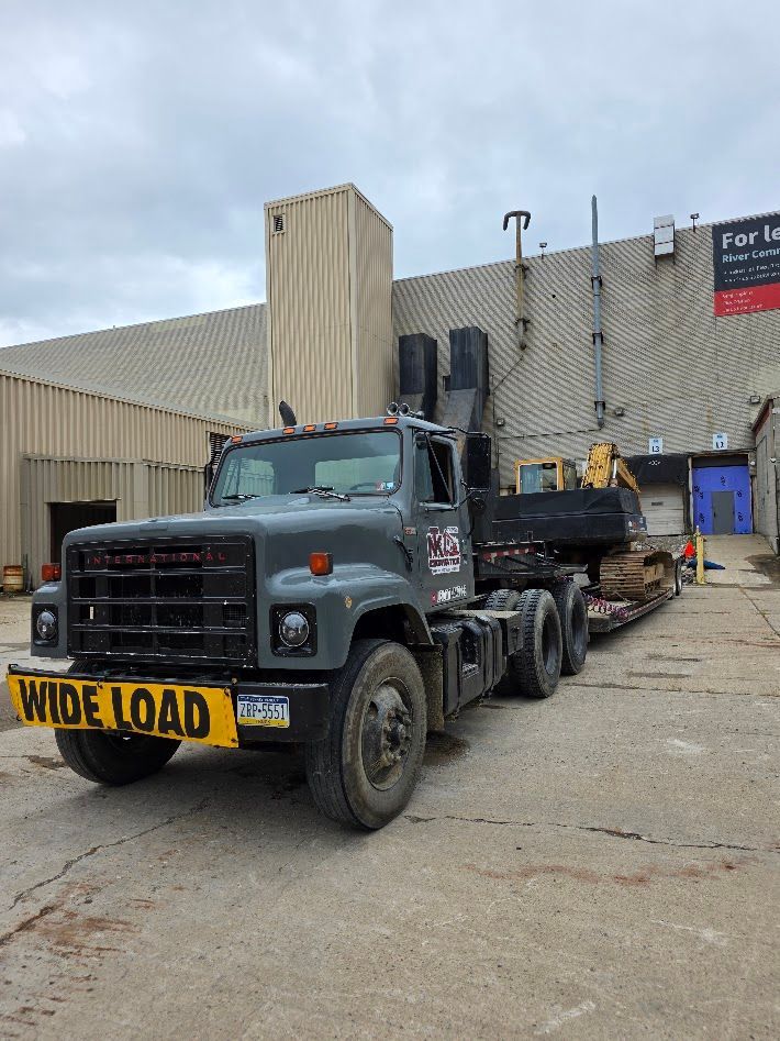 Gray tow truck with a yellow sign parked by an industrial building