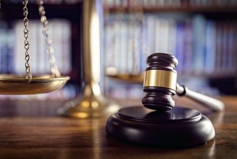 Scales of justice and gavel on a wooden desk, symbolizing law and order.