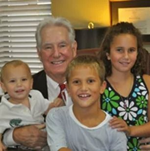 Man smiling with three children; one in his arms.
