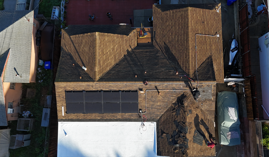 Aerial view of brown-roofed houses and a large white structure in a residential neighborhood.