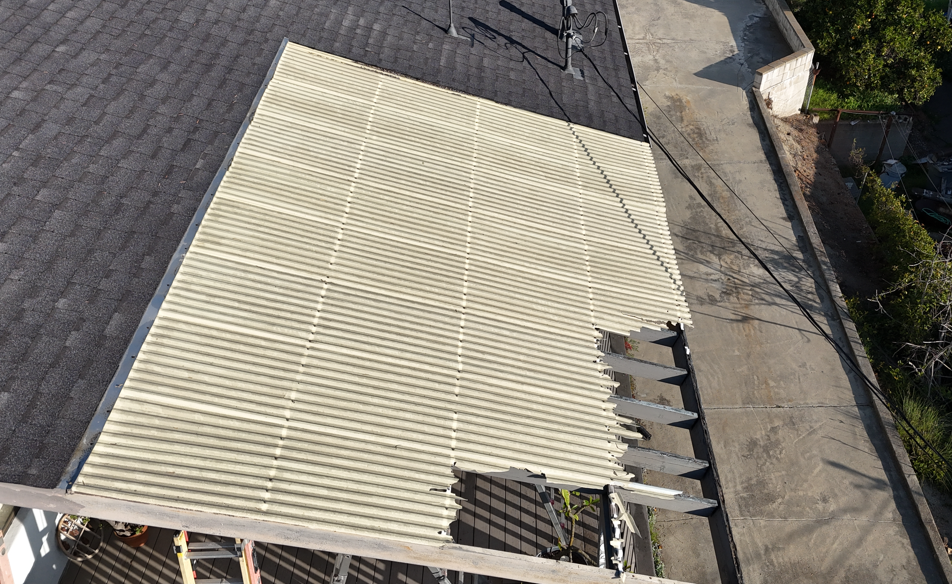 Beige awning torn and sagging over a rooftop beside a dark shingled roof and walkway