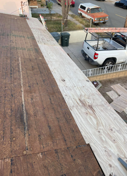 Roof view of a street with parked pickup trucks and a trash bin below.
