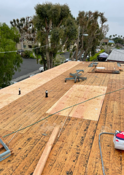 Partially finished plywood rooftop deck with tools, overlooking trees and water