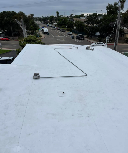White flat rooftop with a cable line and city street view in the distance
