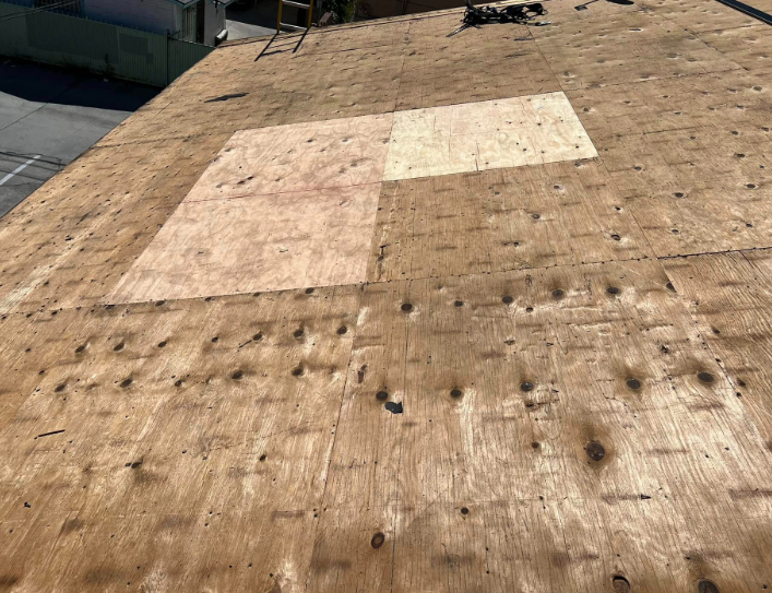 Rooftop covered in weathered plywood with two lighter rectangular patches near the center