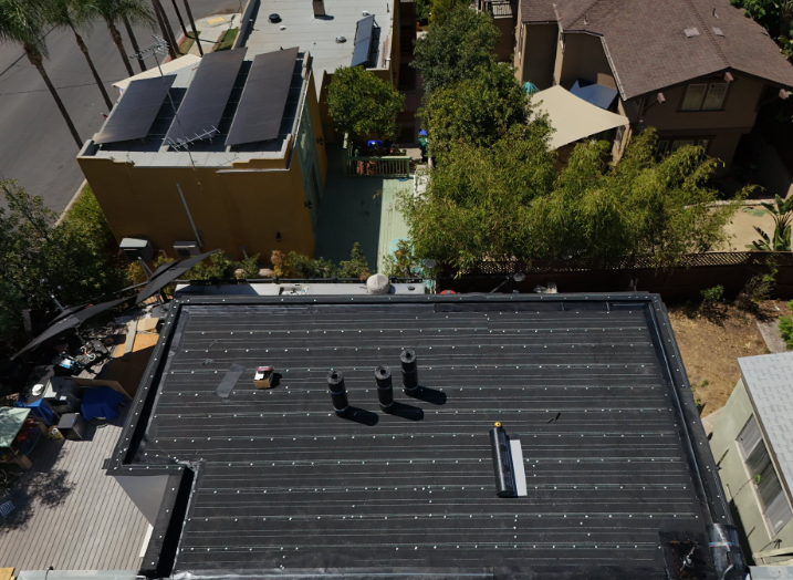 Aerial view of a roof with solar panels and nearby houses in a residential neighborhood