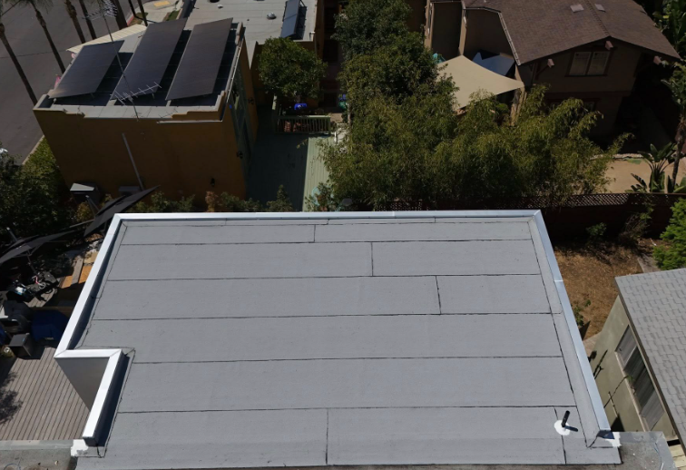 Aerial view of a flat rooftop with solar panels and nearby residential houses.
