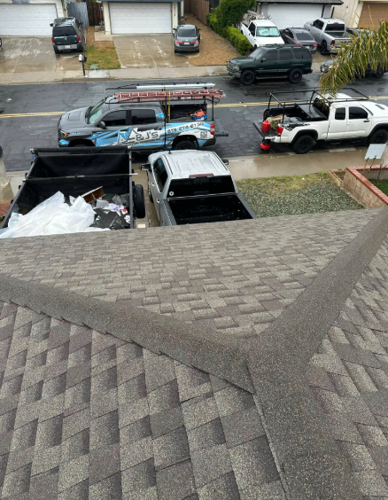 View from a roof onto a flooded street with parked trucks and cars near a curb and driveway