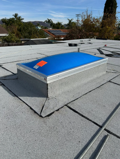 Blue rooftop skylight on a flat gray roof under a clear sky.