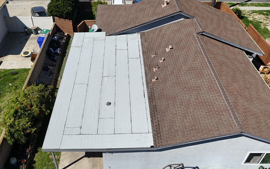Aerial view of a house roof with a large white tarp covering one side and brown shingles on the other.