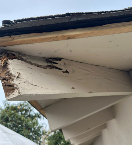 Damaged house eaves with peeling paint and cracked wood under the roofline