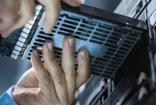 Person installing a hard drive into a server, with hands visible holding the drive.