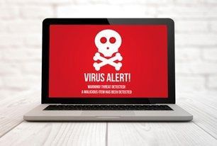 Laptop displaying red screen with skull and crossbones and "VIRUS ALERT!".