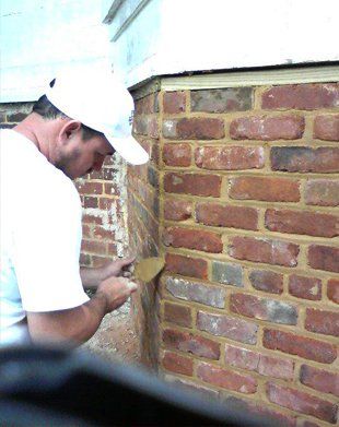 Man with white hat repairing brick wall