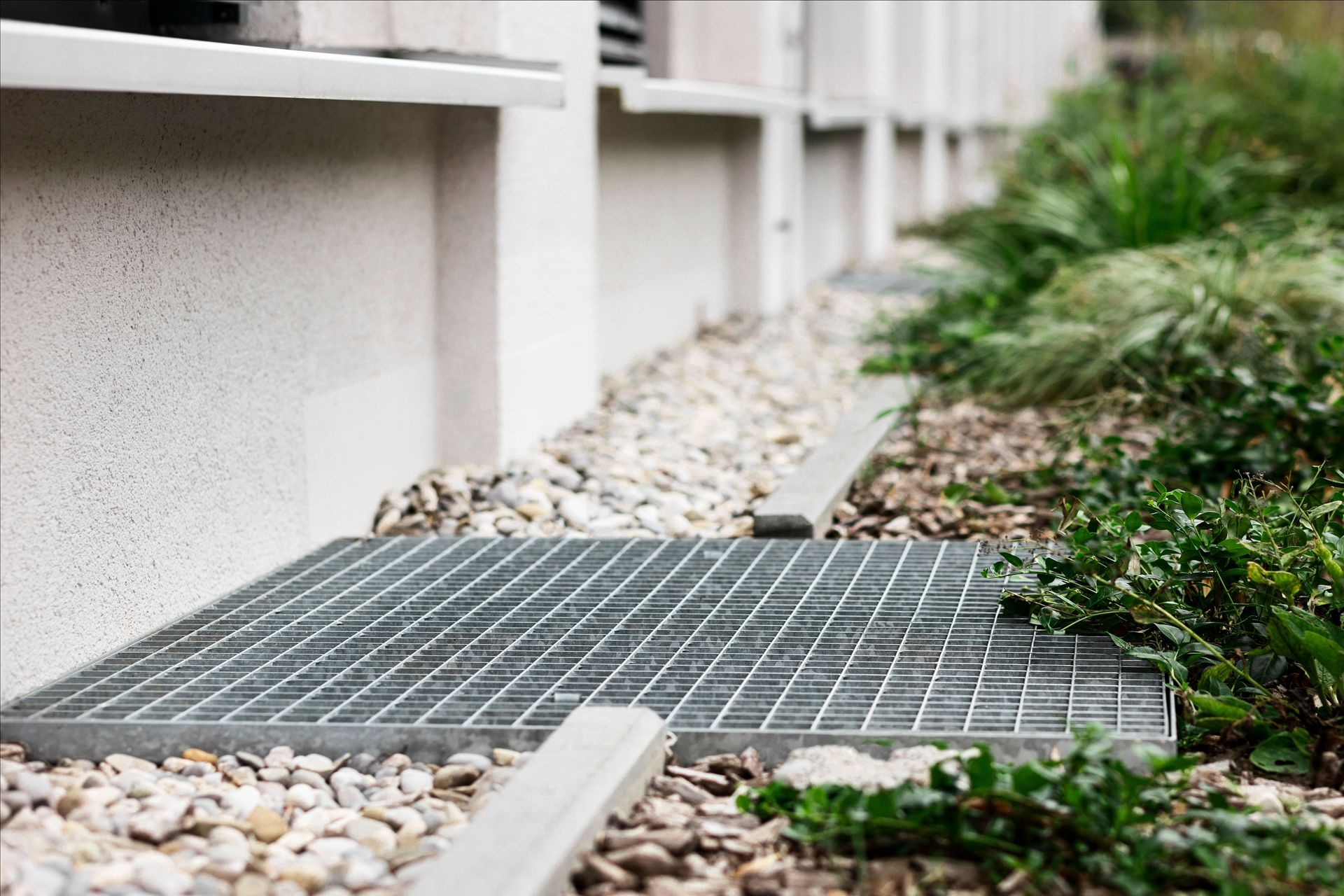 A metal grate is sitting on the ground next to a building.