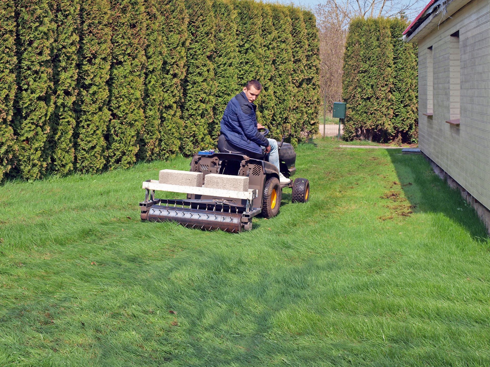 A man is riding a lawn mower on a lush green lawn.