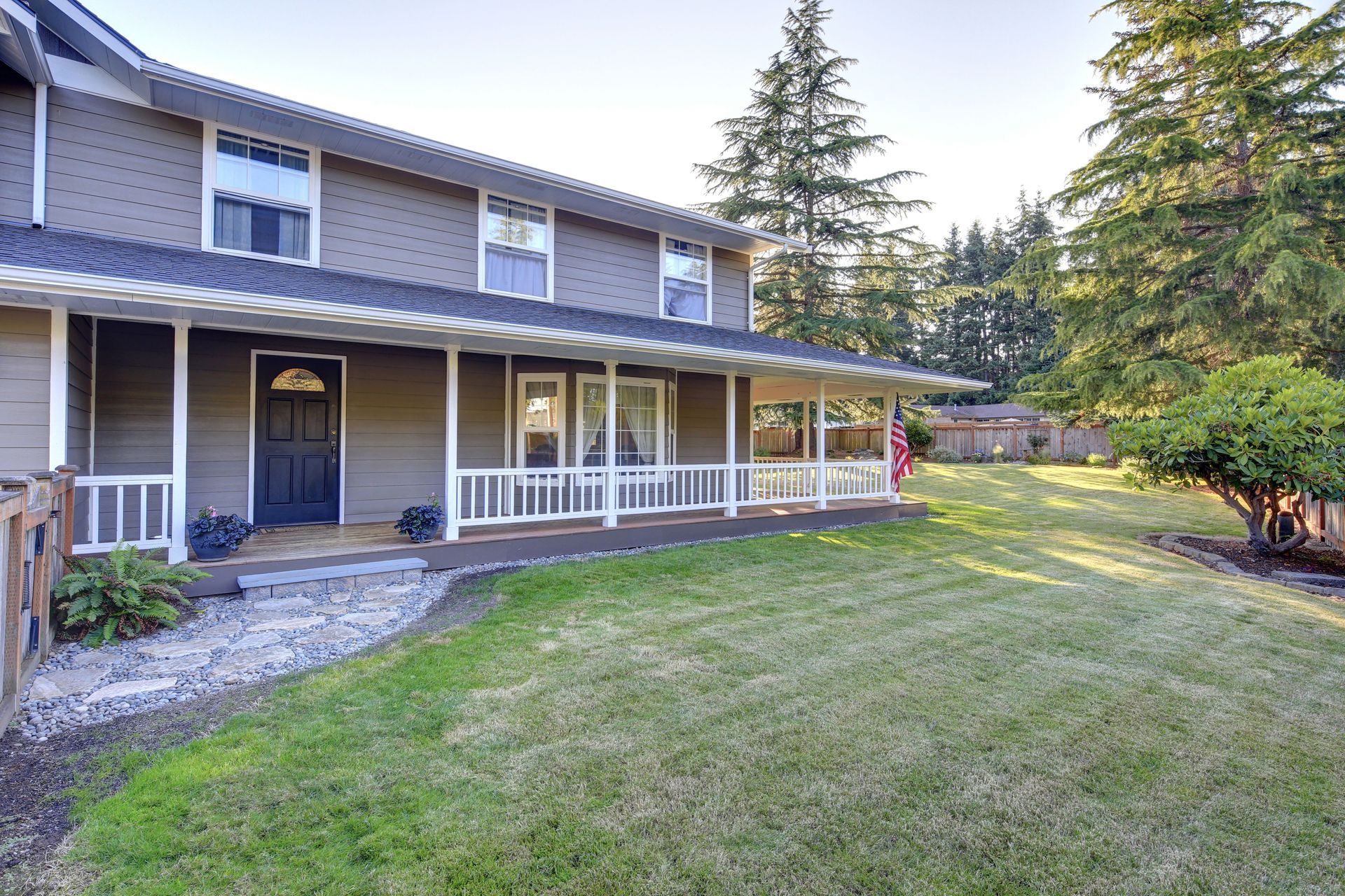 A large house with a large porch and a lush green lawn.